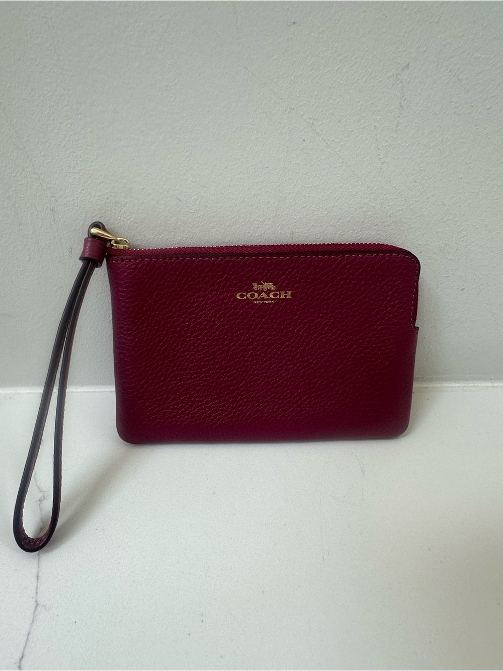 Coach corner zip wristlet in wine plum color.